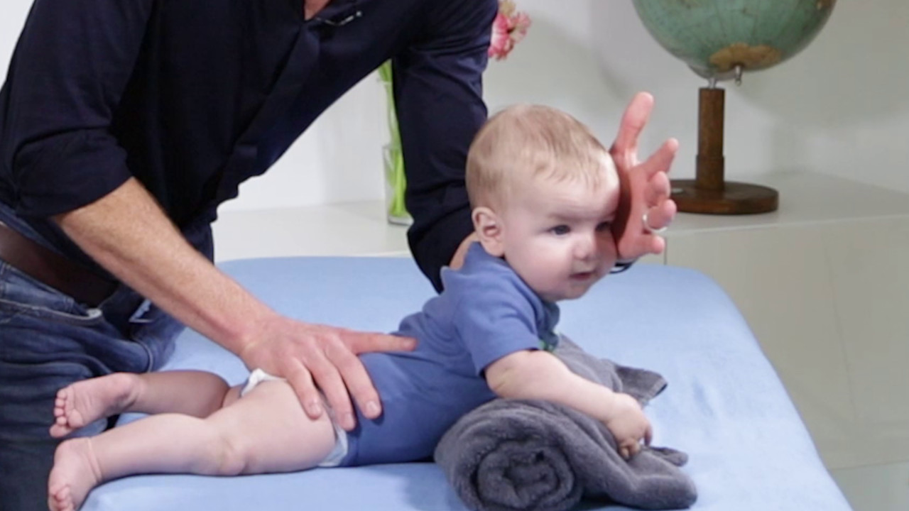 Training der Bauchlage im Säuglingsalter über einer Handtuchrolle