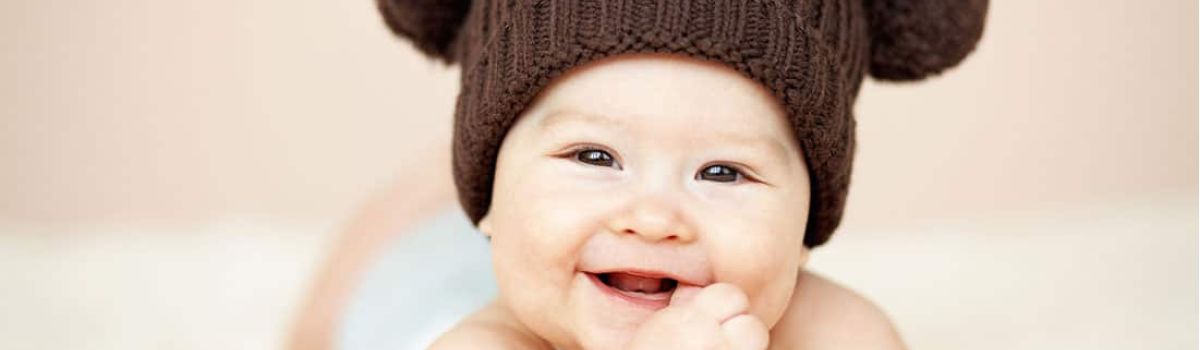 Baby met hoedje lacht naar de camera